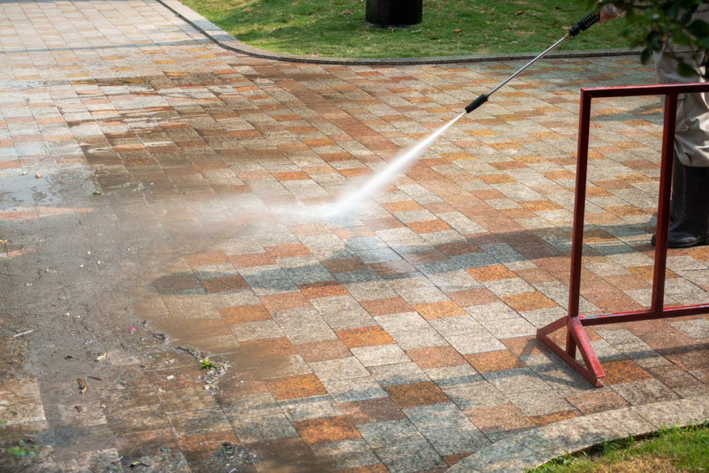 A person using a pressure washer to clean the ground.